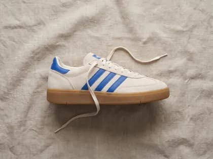 The sneaker shot from above on crumpled linen, one lace trailing loose.